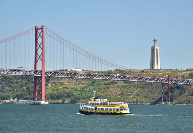 Cacilhas ferry crossing the Tagus river in Lisbon with Cristo Rei visible in the background