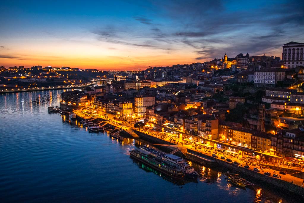 Porto's Ribeira waterfront at golden hour — terracotta rooftops and colourful houses reflected in the Douro river